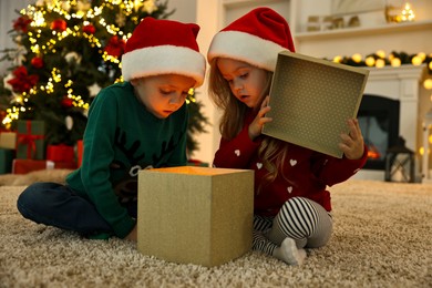 Photo of Little kids opening magic Christmas box on floor at home