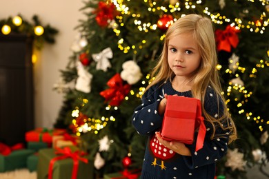 Photo of Little girl with Christmas gift at home