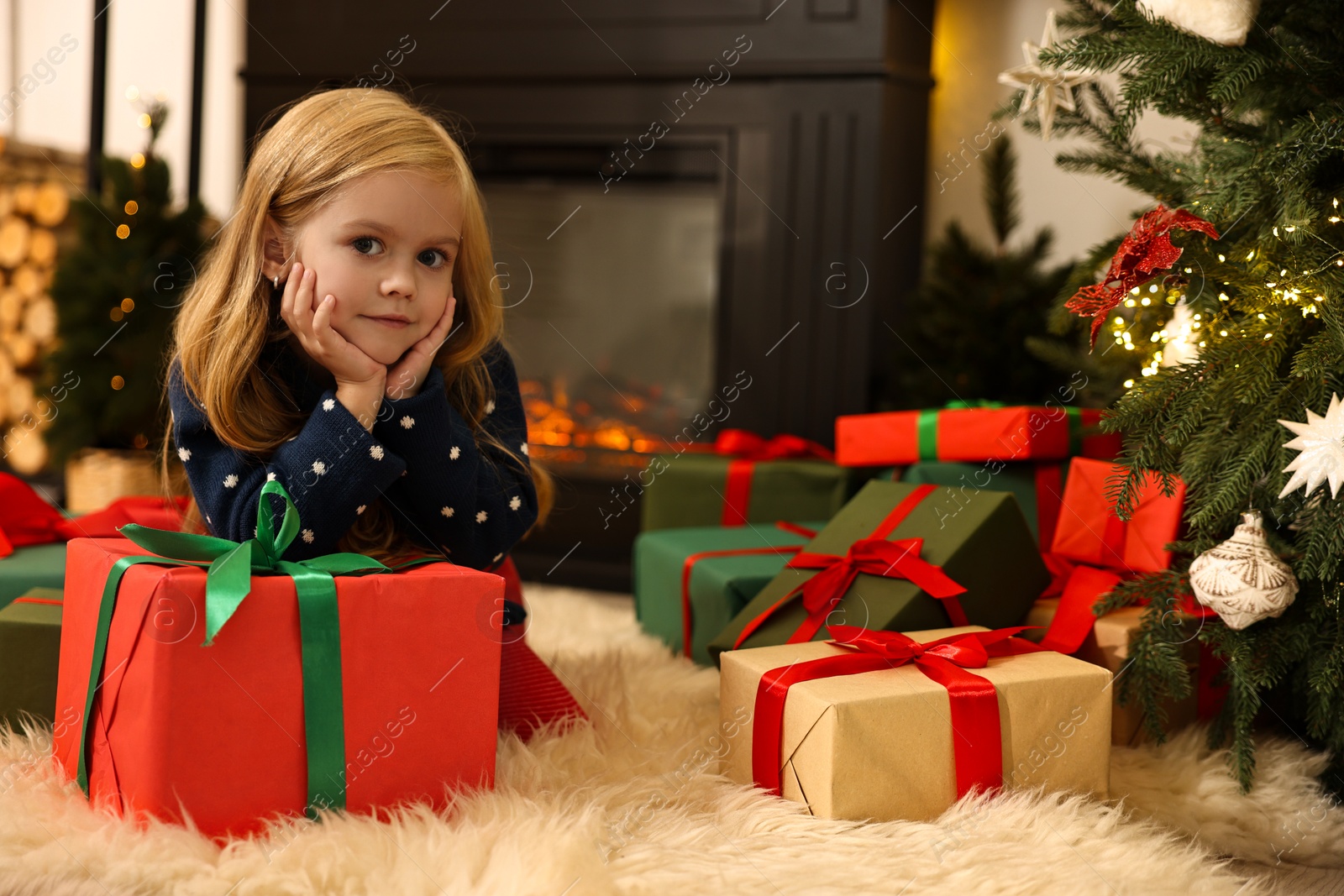 Photo of Little girl with Christmas gifts on floor at home