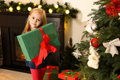 Photo of Little girl with Christmas gift at home