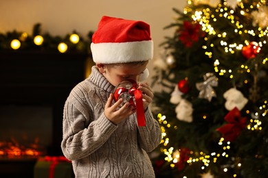 Photo of Little boy with Christmas ornament at home