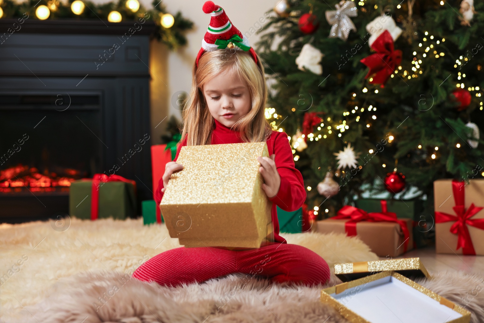 Photo of Little girl opening Christmas gift on floor at home