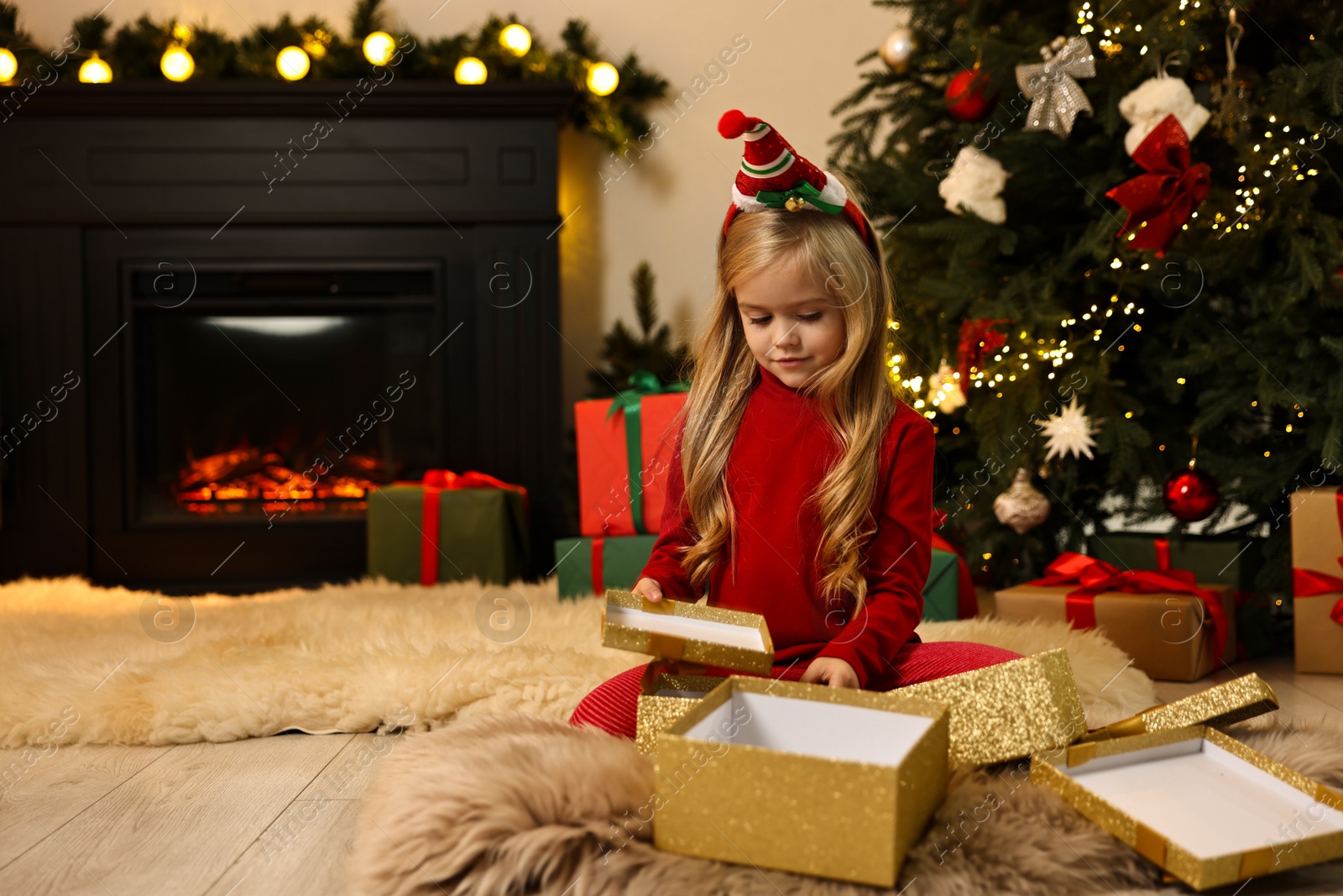 Photo of Little girl opening Christmas gift on floor at home