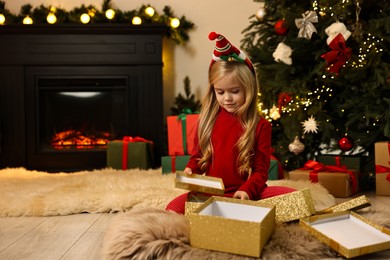 Photo of Little girl opening Christmas gift on floor at home