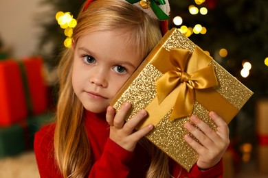 Photo of Little girl with Christmas gift at home