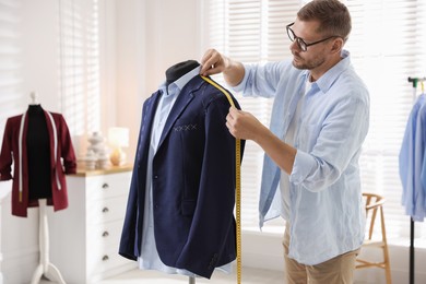 Photo of Man measuring black jacket with tape in atelier