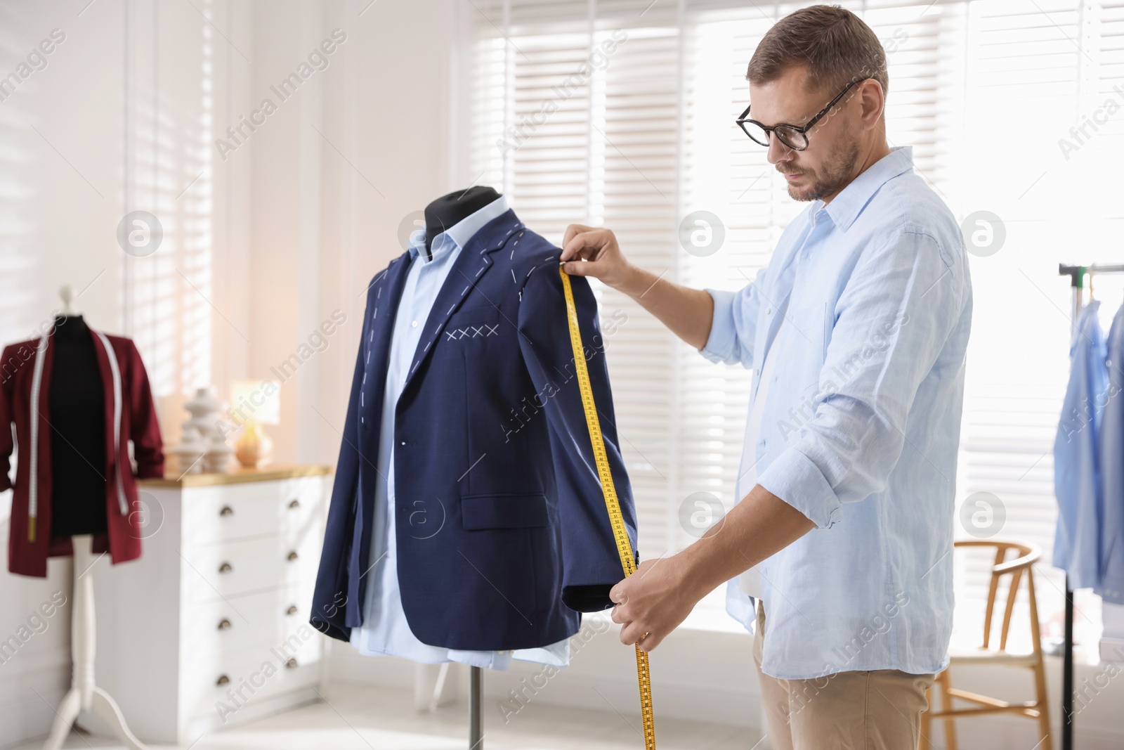 Photo of Man measuring black jacket with tape in atelier