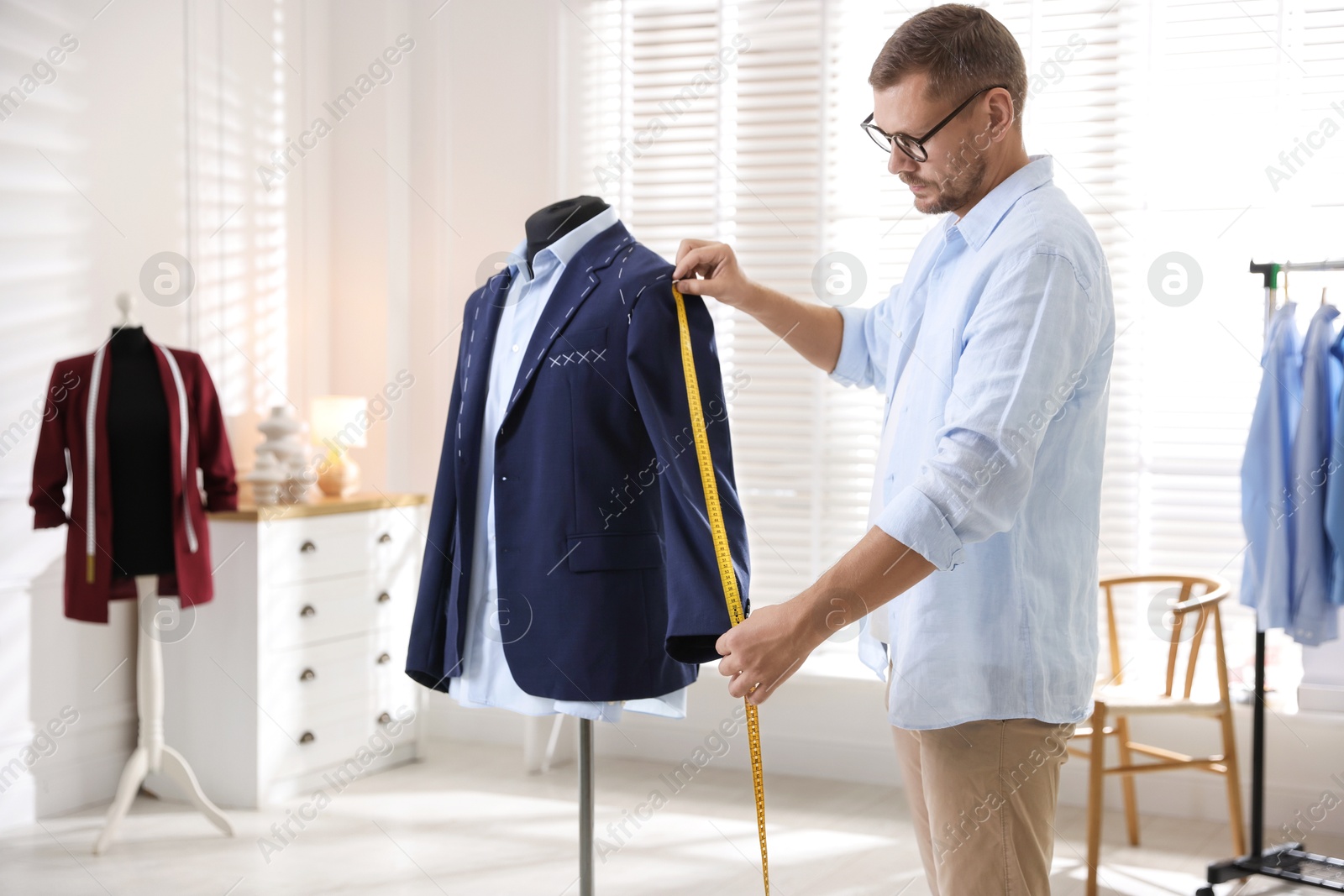 Photo of Man measuring black jacket with tape in atelier