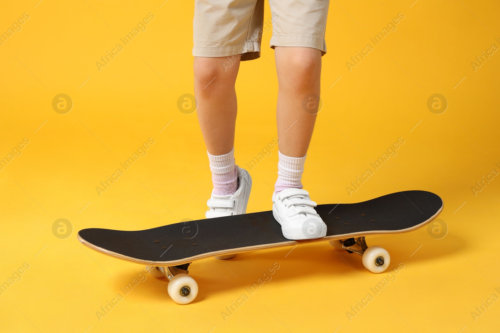 Photo of Little girl with skateboard on yellow background, closeup