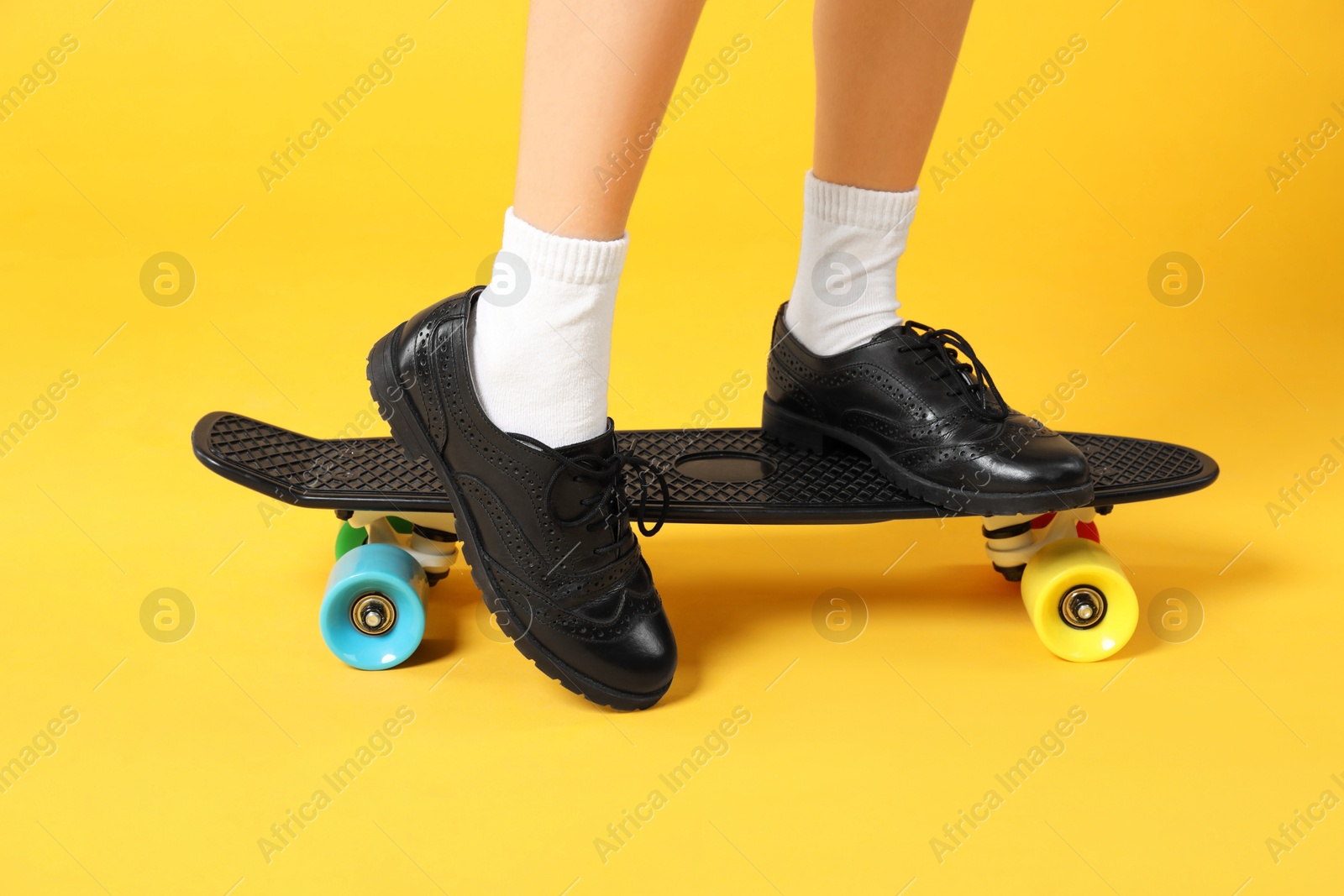 Photo of Little girl with penny board on yellow background, closeup