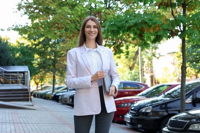 Photo of Portrait of young woman with laptop wearing stylish suit outdoors