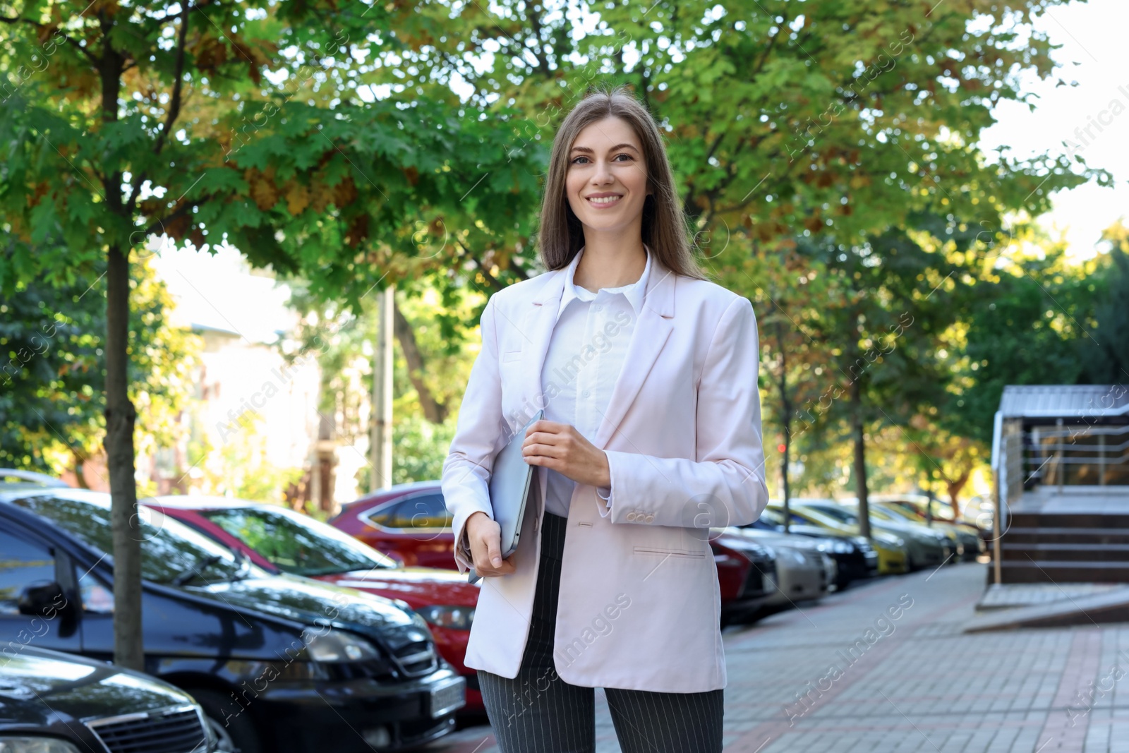 Photo of Portrait of young woman with laptop wearing stylish suit outdoors