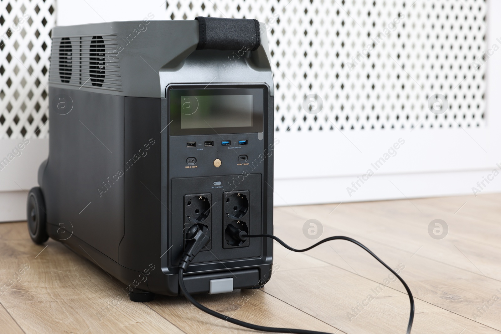 Photo of Modern portable power station on floor indoors, space for text