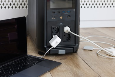 Photo of Modern portable power station, charging attached devices indoors, closeup