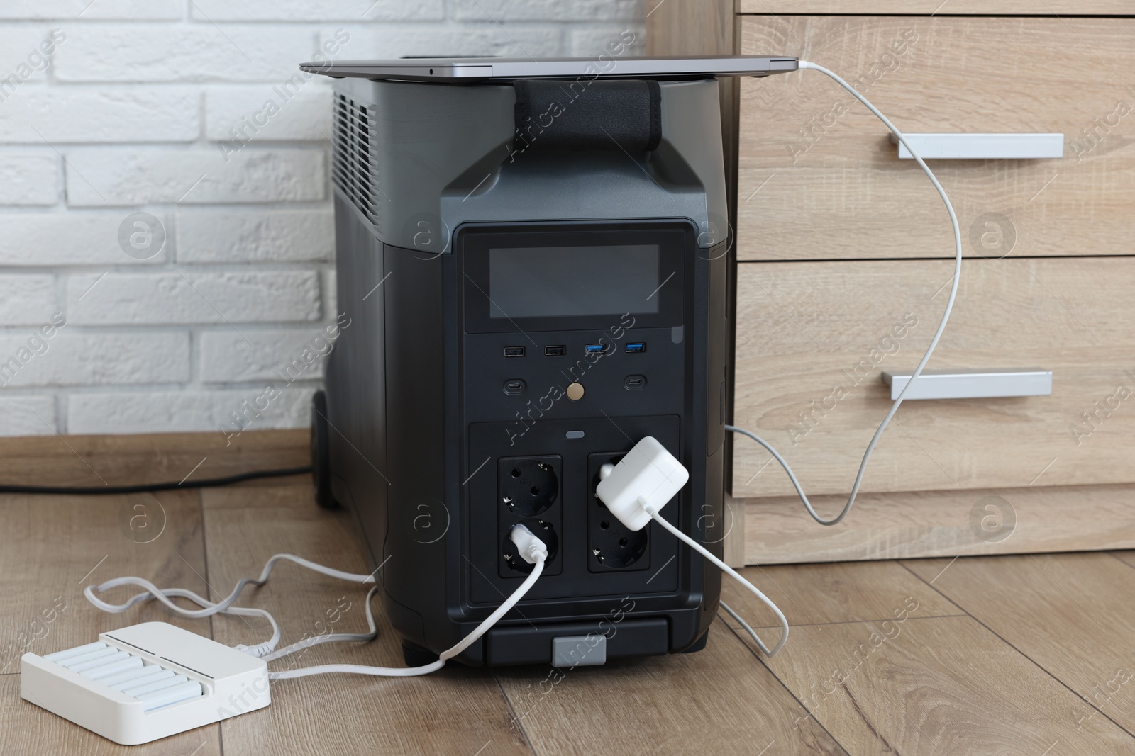 Photo of Modern portable power station, charging attached devices indoors