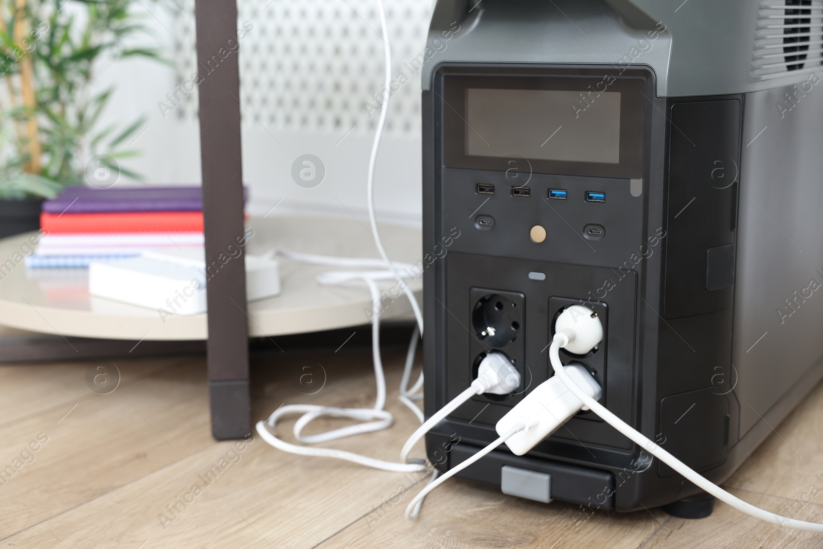 Photo of Modern portable power station on floor indoors, closeup