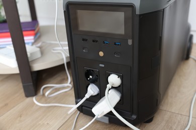 Photo of Modern portable power station on floor indoors, closeup