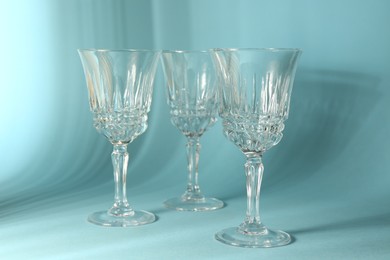 Photo of Empty wine glasses casting beautiful shadows on light blue background