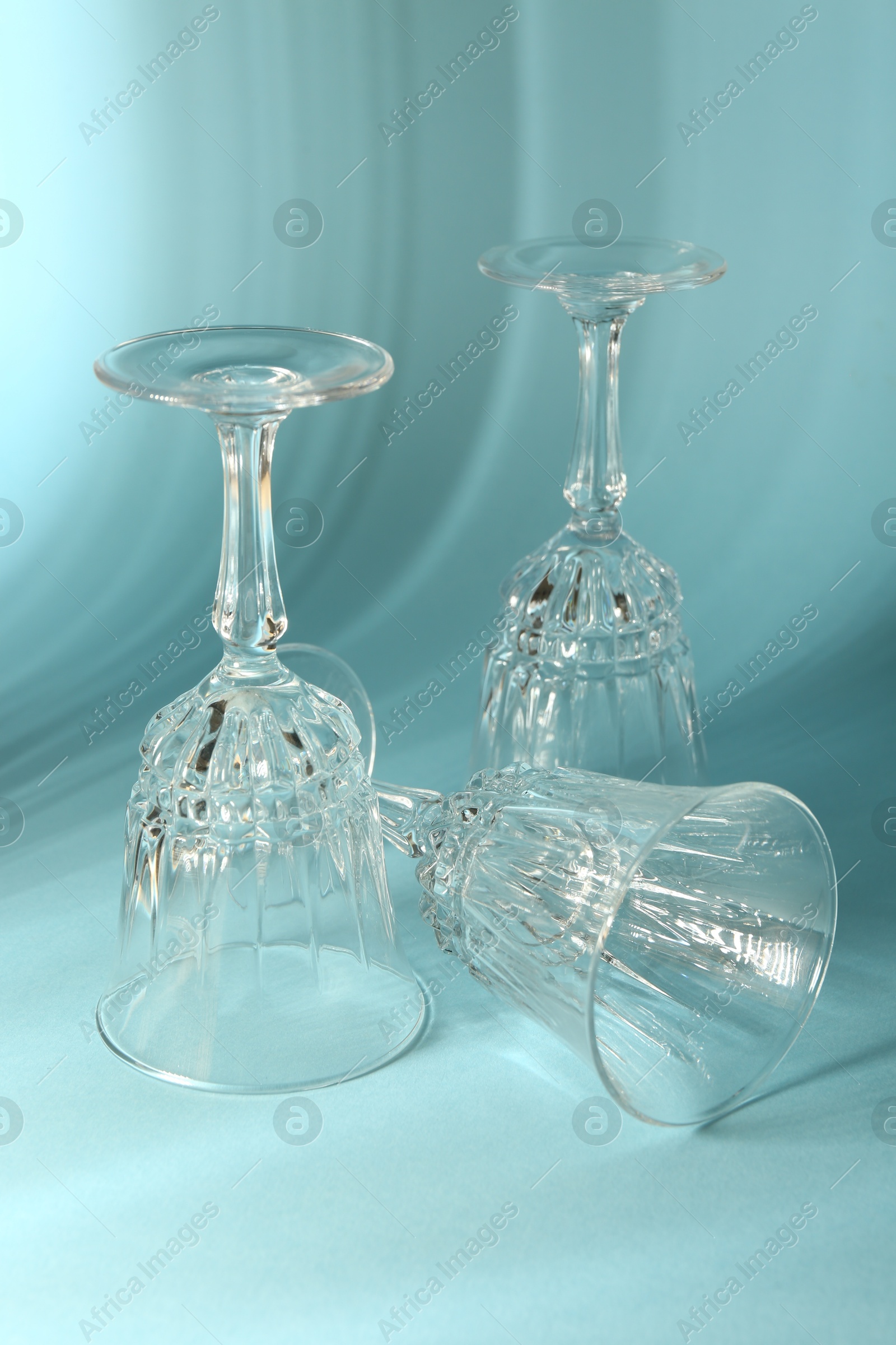 Photo of Empty wine glasses casting beautiful shadows on light blue background