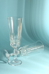 Photo of Two empty wine glasses casting beautiful shadows on light blue background