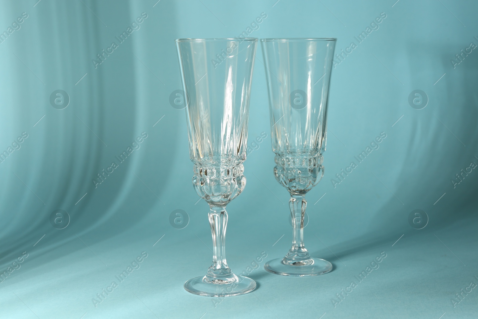 Photo of Two empty wine glasses casting beautiful shadows on light blue background