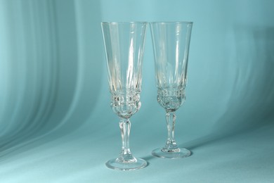 Photo of Two empty wine glasses casting beautiful shadows on light blue background