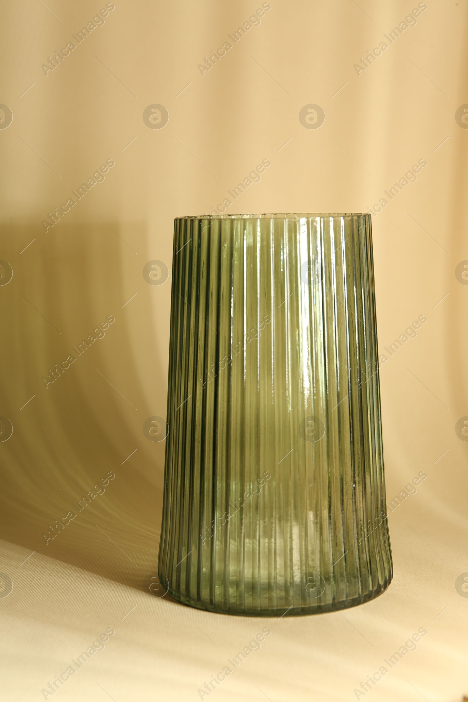 Photo of Empty glass vase casting beautiful shadows on beige background