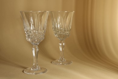 Photo of Two empty wine glasses on beige background, space for text