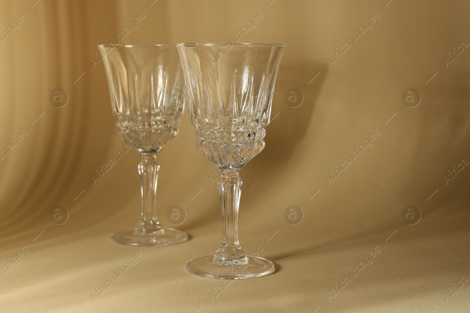 Photo of Two empty wine glasses on beige background, space for text