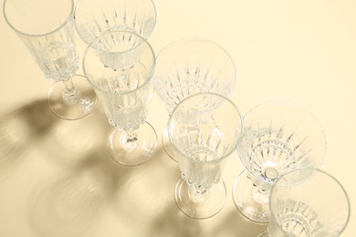 Photo of Empty wine glasses casting beautiful shadows on beige background, above view