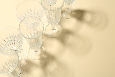 Photo of Empty wine glasses casting beautiful shadows on beige background, above view. Space for text