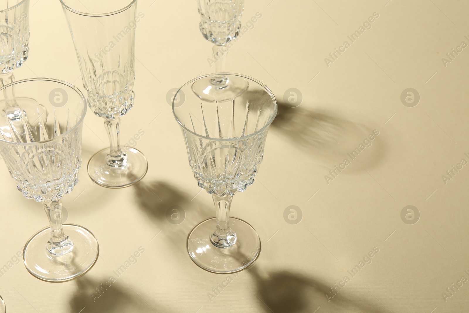 Photo of Empty wine glasses casting beautiful shadows on beige background, space for text