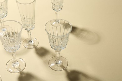 Photo of Empty wine glasses casting beautiful shadows on beige background, space for text