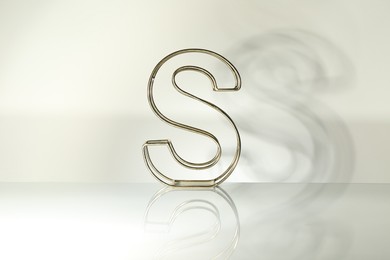 Photo of Stylish golden decor in shape of letter S on white background