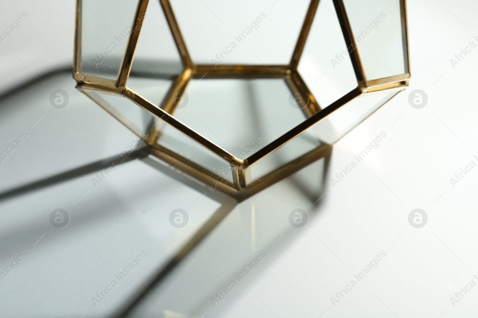 Photo of Stylish golden decor casting beautiful shadows on white table, closeup