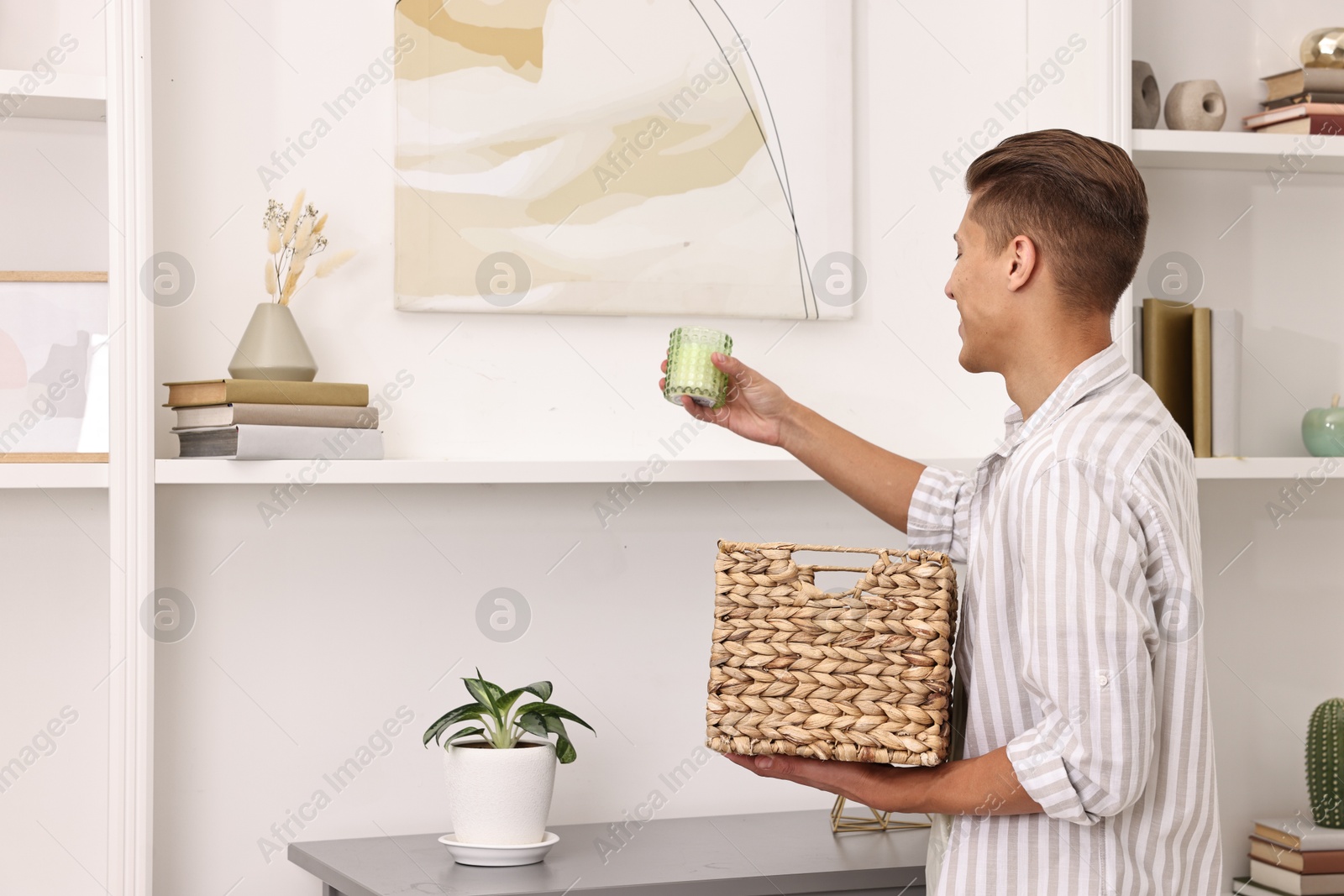 Photo of Male decorator arranging decor onto shelf at home