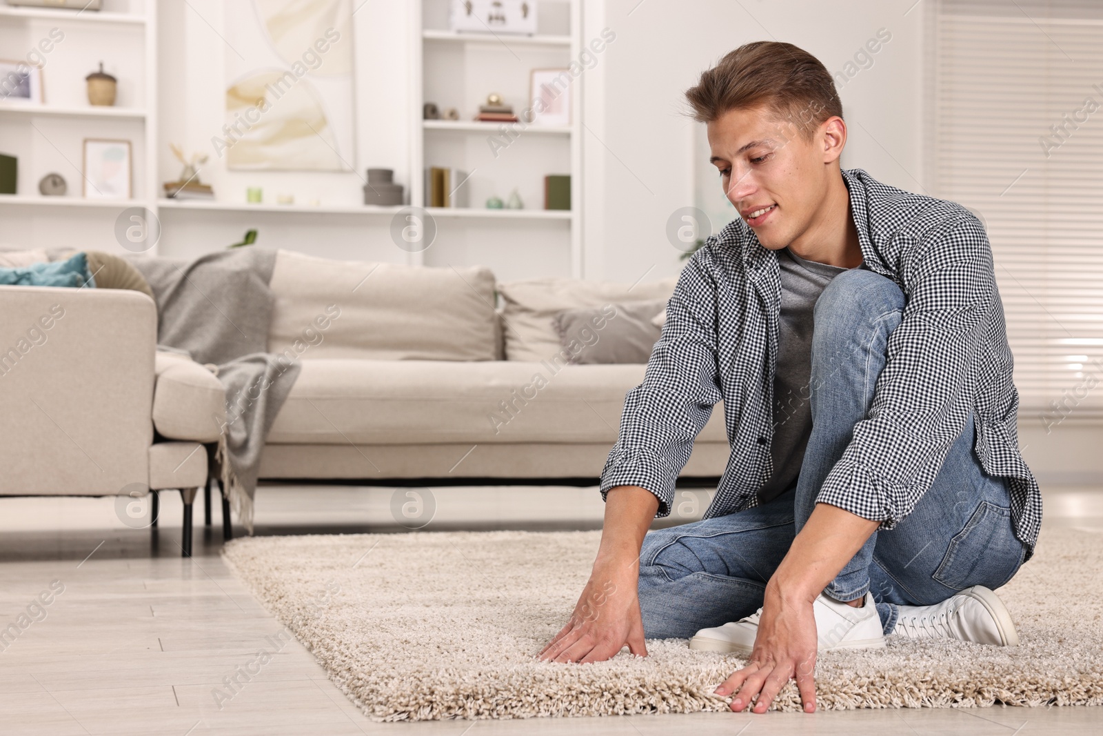 Photo of Smiling decorator placing beige carpet indoors. Space for text