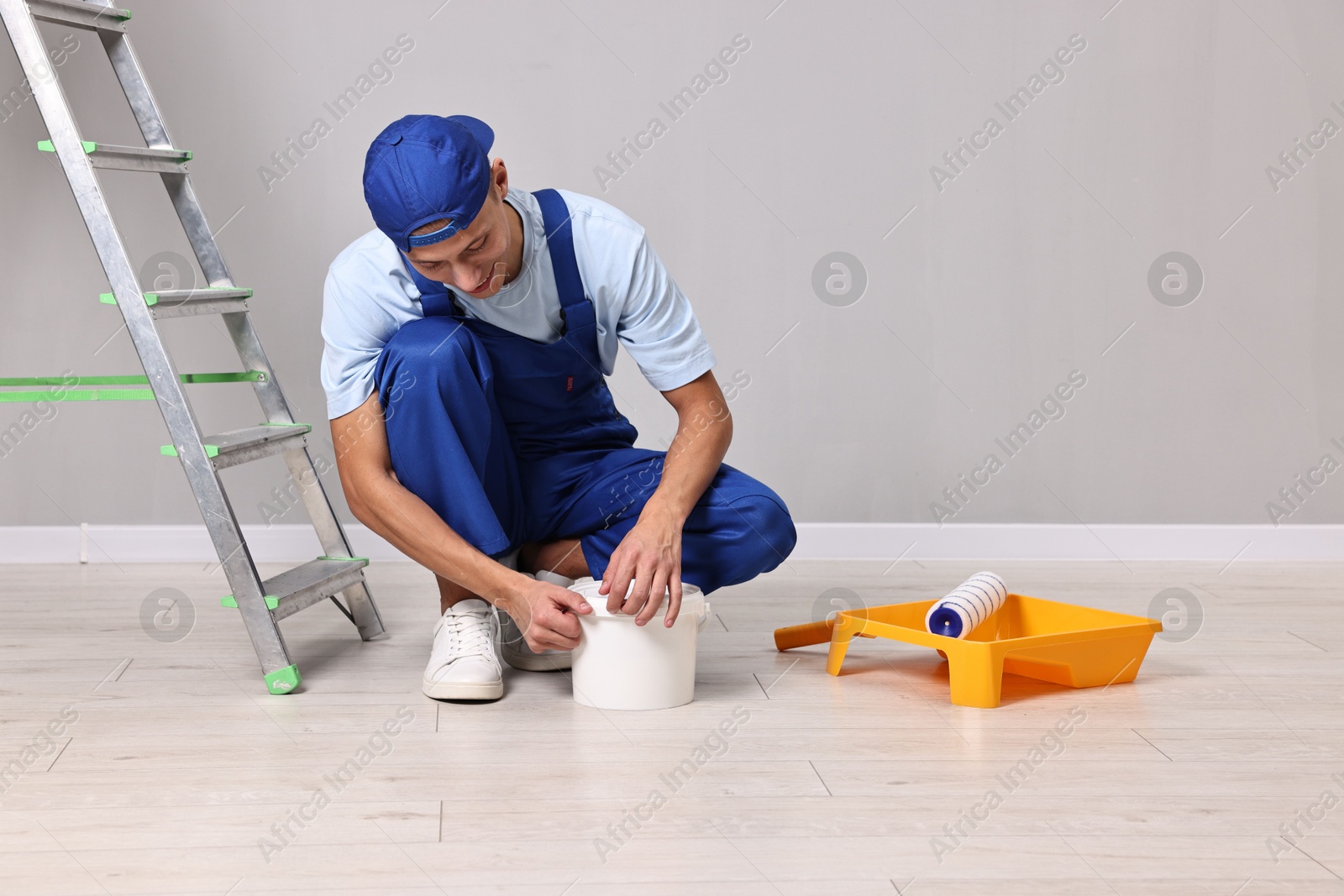 Photo of Smiling handyman preparing to painting wall indoors