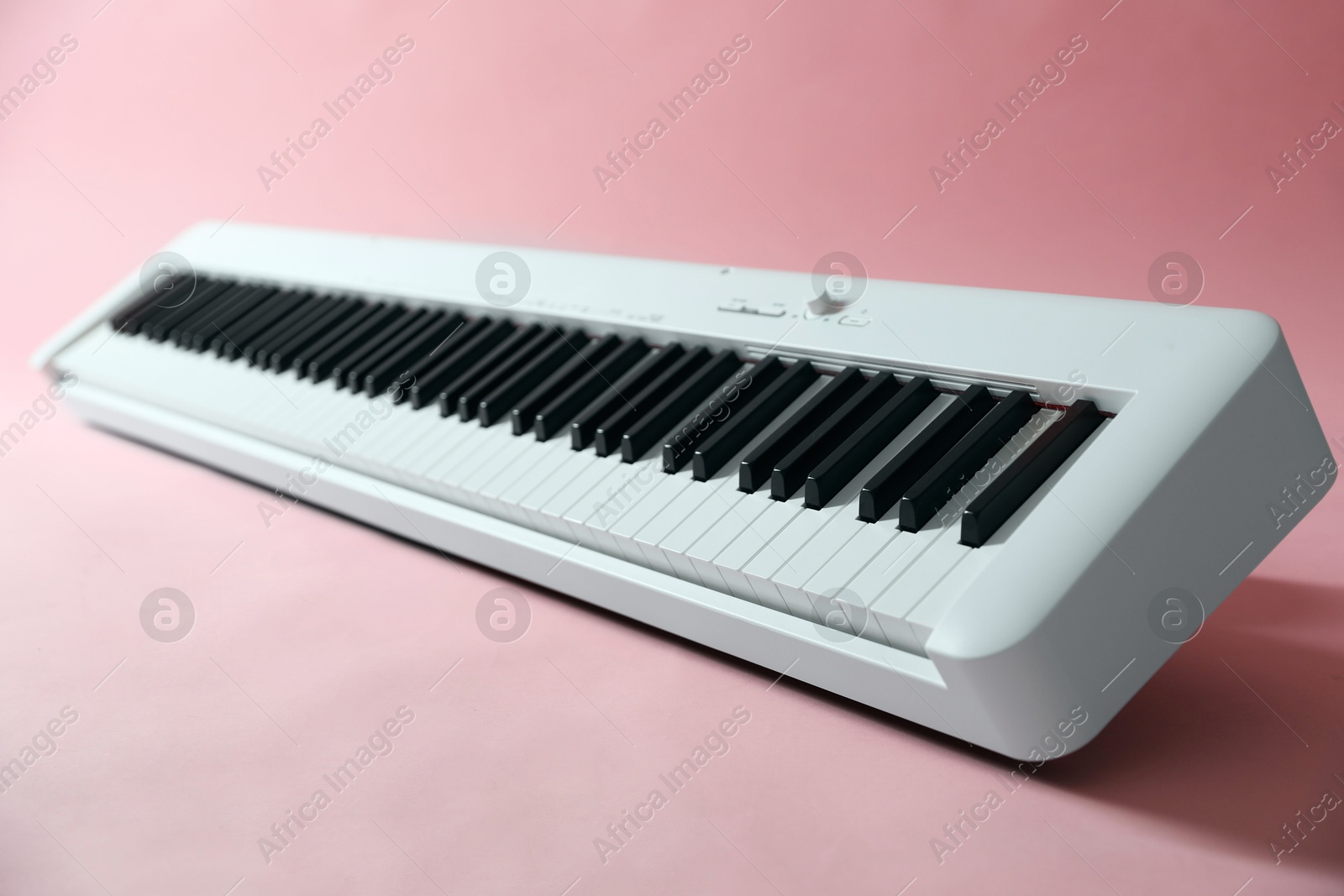 Photo of Synthesizer on pink background, closeup. Electronic musical instrument