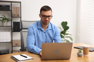 Photo of Programmer working on laptop at wooden desk indoors