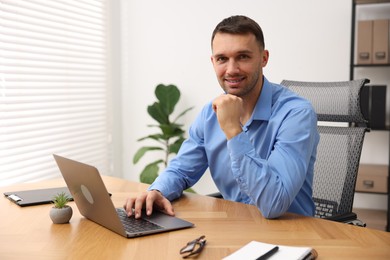 Photo of Programmer with laptop at wooden desk indoors