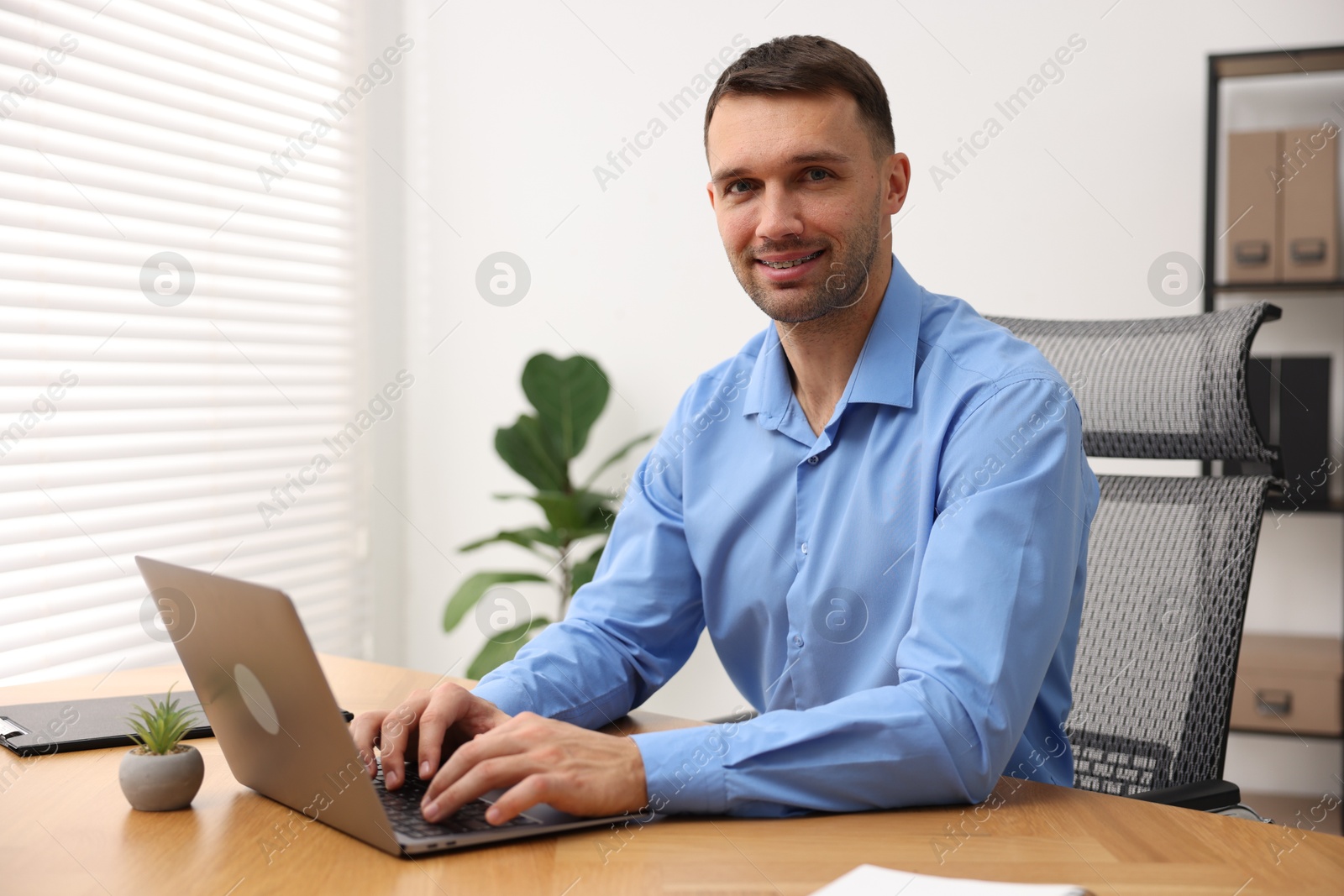 Photo of Programmer with laptop at wooden desk indoors