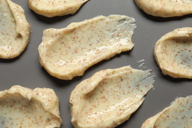 Photo of Smears of body scrub on grey background, flat lay