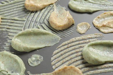 Photo of Samples of body scrubs on grey background, closeup