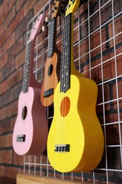 Three colorful ukulele on brick wall indoors