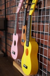 Photo of Three colorful ukulele on brick wall indoors