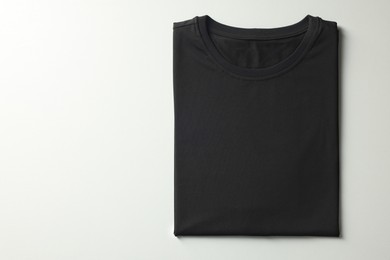 Photo of Blank black t-shirt on white background, top view. Mockup for design