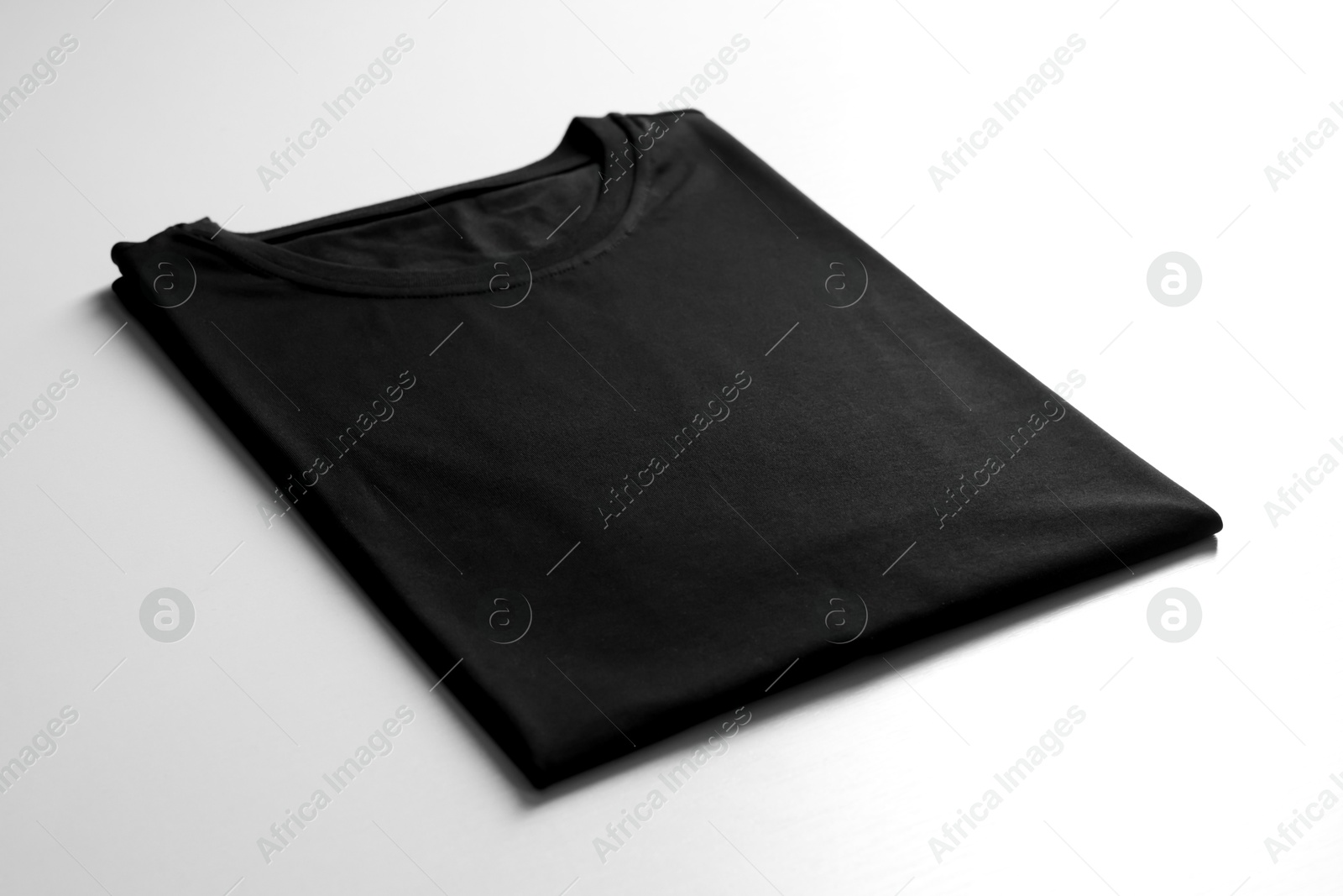 Photo of Blank black t-shirt on white background, closeup. Mockup for design