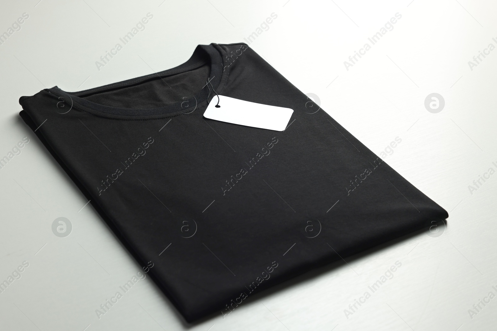 Photo of Blank black t-shirt on white background, closeup. Mockup for design