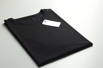 Photo of Blank black t-shirt on white background, closeup. Mockup for design